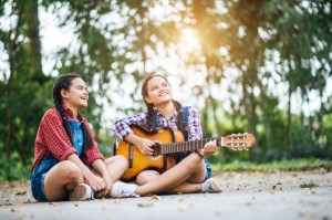 dos-chicas-relajarse-tocando-la-guitarra-y-cantar-una-cancion_1150-4112